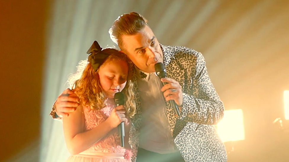 Robbie Williams duets with fans daughter for Priceless Surprise